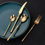 Matte gold flatware set with antique finish arranged on a wooden table