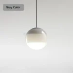 Green glass pendant lamp with a visible bulb inside, creating a soft glow in a restaurant.