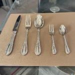 Elegant stainless steel flatware set with mirror finish arranged on a wooden table