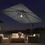 Goldoma large patio umbrella with lights illuminating a 9x9 FT square cantilever umbrella with solar LED lights in a bac