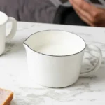 Enamel baking measuring cup with dual scale markings on a kitchen counter