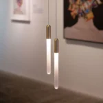 Close-up of the acrylic pendant light showing its sleek, elongated shape and warm glow.