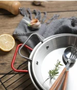 Stainless steel paella pan with double ears on a stove