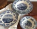 Vintage blue floral dinner set arranged on a wooden table with plates, bowls, and cups