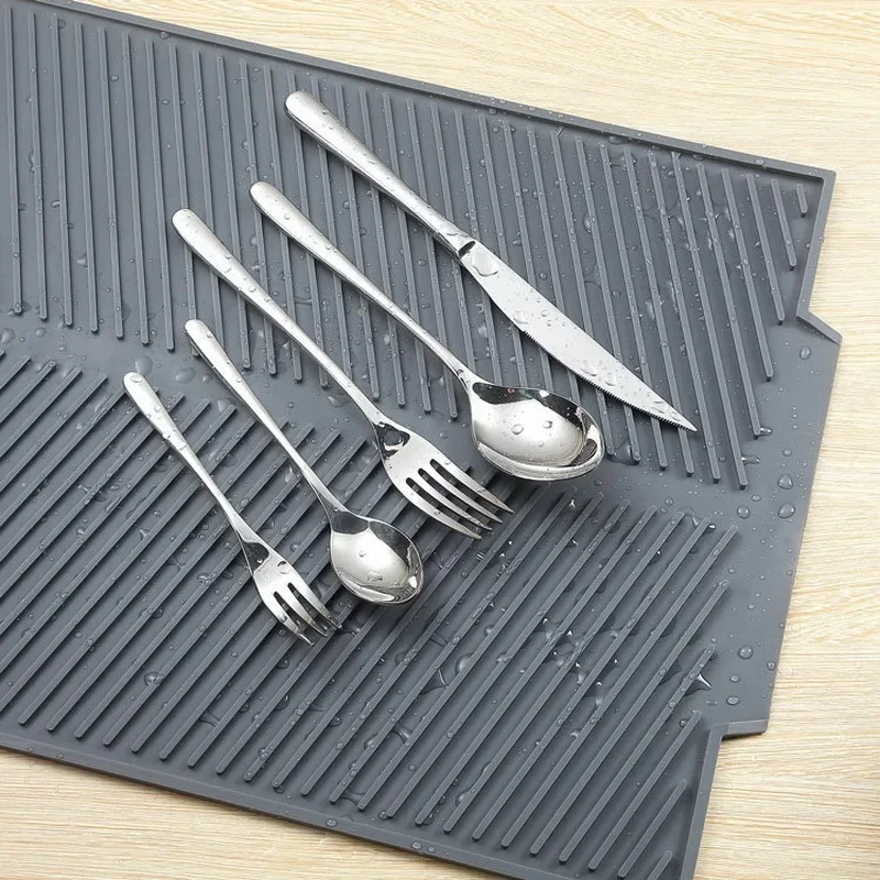 Silicone dish drying mat with pots and utensils on kitchen counter