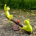 Frog miniature playground set with seesaw, placed on mossy ground in a micro landscape garden.