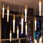Acrylic pendant light suspended above a bedside table in a cozy bedroom.