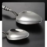 Elegant French stainless steel cutlery set with pointed tail handles on a wooden table