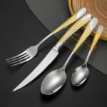 Elegant gold flatware set with steak knife, fork, and spoon on a dark table