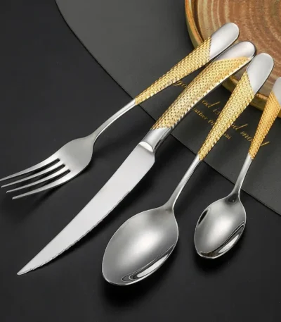 Elegant gold flatware set with steak knife, fork, and spoon on a dark table