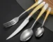 Elegant gold flatware set with steak knife, fork, and spoon on a dark table
