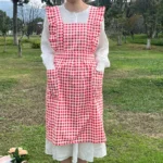 Woman wearing a cotton apron for baking with fresh plaid pattern and ruffled edges in a rustic kitchen