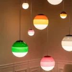 Pink glass pendant lamp shown against a dark wall, highlighting its bright color.