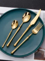 Matte gold flatware set with antique finish arranged on a wooden table