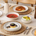 Elegant ceramic plates set with dinner plates, dessert plates, cereal bowls, and soup bowls arranged on a wooden table