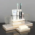 Golden soap dispenser and toothbrush holder on marble tray.