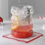 Set of glass cups with straws on a wooden table, filled with iced tea and lemon