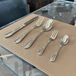 Elegant stainless steel flatware set with mirror finish arranged on a wooden table