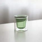 Clear double wall insulated glass mug with espresso coffee on wooden table