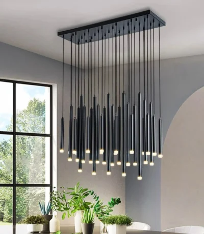 Modern gold pendant light with clear glass shade hanging over a wooden dining table.