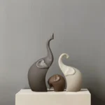 Matte white ceramic elephant figurine placed on a stack of books in a cozy living room.