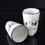 Mouthwash cup next to a toothbrush holder, both with matching blue floral design, on a vanity.