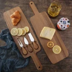 Acacia cheese board set with cheese knives and wooden cutting board on a table