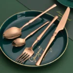 Goldoma 16-piece stainless steel silverware set with forks, knives, and spoons on a wooden table