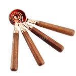 Set of stainless steel measuring cups with copper and rose gold finishes on wooden stand