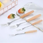 Stainless steel flatware set with wooden handles displayed on a table