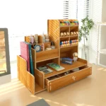 Wooden office accessory with a drawer pulled out, containing paper clips and erasers.