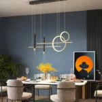 Three gold pendant lights aligned over a long dining table in a contemporary setting.