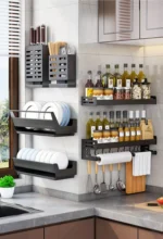 Stainless steel wall mounted dish rack holding plates and bowls in a modern kitchen