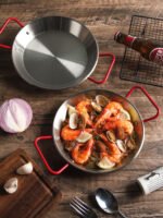 Stainless steel paella pan with double ears on a stove