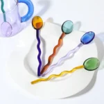 Borosilicate glass mug with coffee and glass spoon on a wooden table