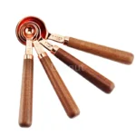 Set of stainless steel measuring cups with copper and rose gold finishes on wooden stand