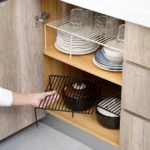 Adjustable dish drying rack with multiple tiers holding plates, bowls, and spice jars on a kitchen counter