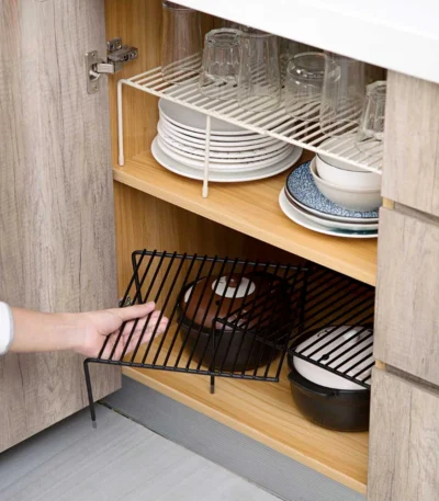 Adjustable dish drying rack with multiple tiers holding plates, bowls, and spice jars on a kitchen counter
