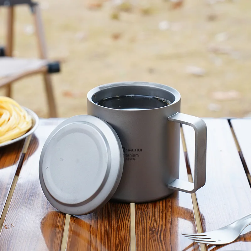 Double wall titanium mug with lid and tea strainer on a wooden table