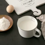 Enamel baking measuring cup with dual scale markings on a kitchen counter
