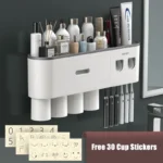 Toothpaste dispenser dispensing paste onto a toothbrush, with holder and cup in background.