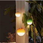 Green glass pendant lamp in a kitchen island setting with bar stools and pendant lights.