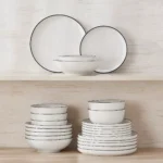 Elegant ceramic plates set with dinner plates, dessert plates, cereal bowls, and soup bowls arranged on a wooden table