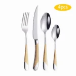 Elegant gold flatware set with steak knife, fork, and spoon on a dark table