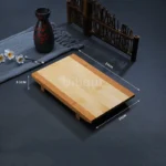 Bamboo sushi serving tray with assorted sushi rolls and sashimi on a wooden table