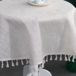 Round linen tablecloth with tassels on a dining table