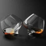 Rotating whiskey glass on a wooden table with amber liquid swirling inside