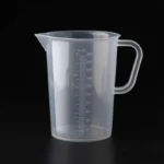 Transparent plastic lab beaker with measurement scale on kitchen counter