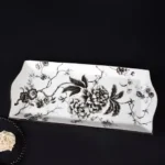 Soap dish with a raised ribbed pattern, holding a round soap bar, on a marble countertop.