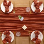 Boho cheesecloth table runner and napkins set as rustic table linens on a wooden table